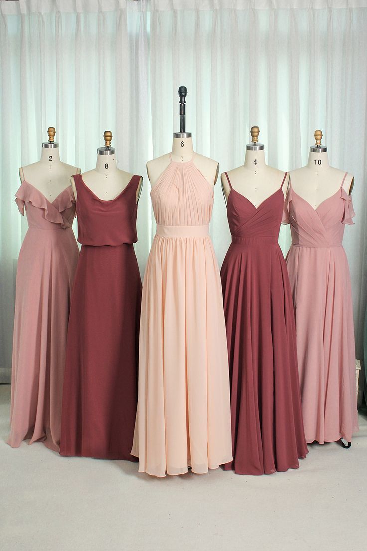 four bridesmaid dresses are lined up on mannequins in front of a window