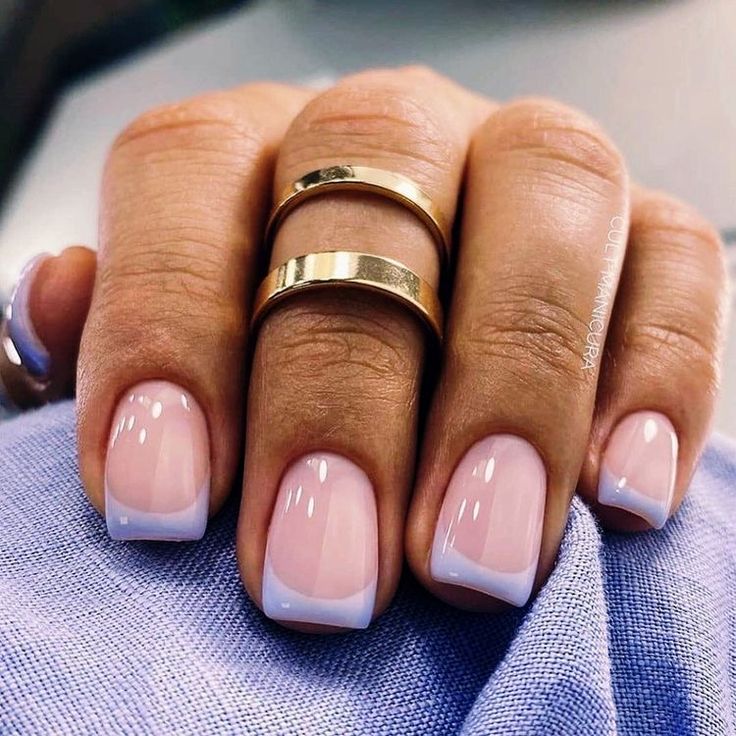 a woman's hand with two gold rings on her fingers and one pink manicure