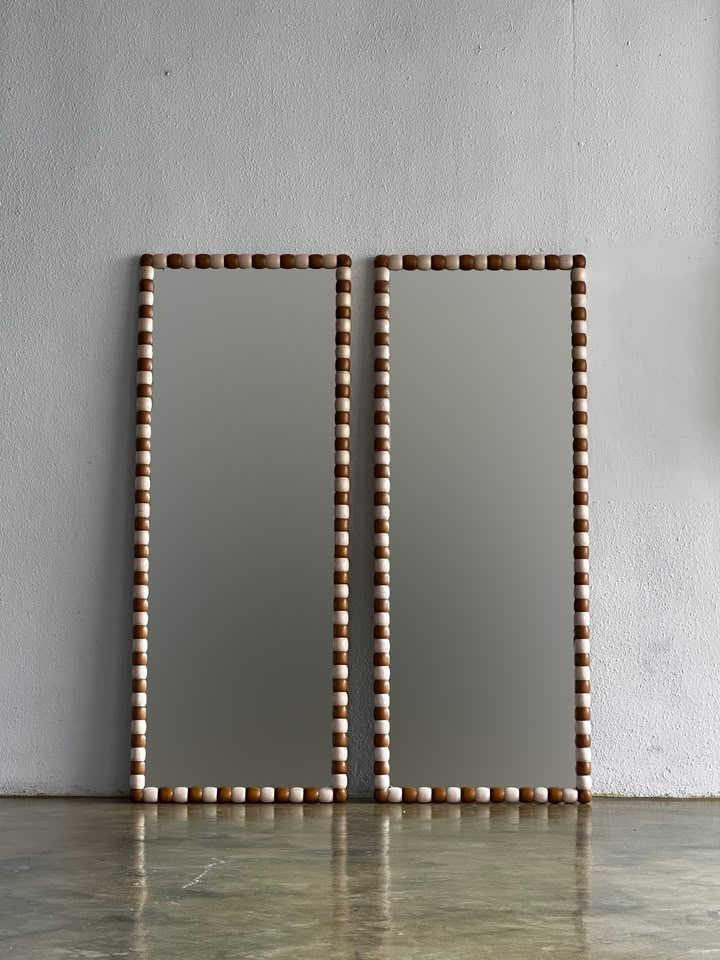 two square mirrors with beaded edges against a white wall