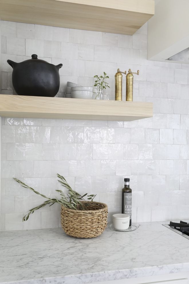 a kitchen with white marble counter tops and shelves above the stove top is a potted plant