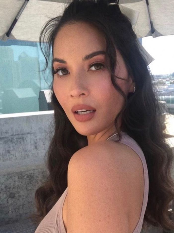 a close up of a person wearing a top and an umbrella over her head with buildings in the background