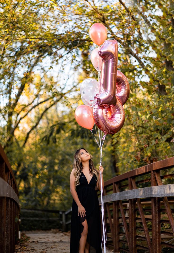 a woman is holding some balloons in the air