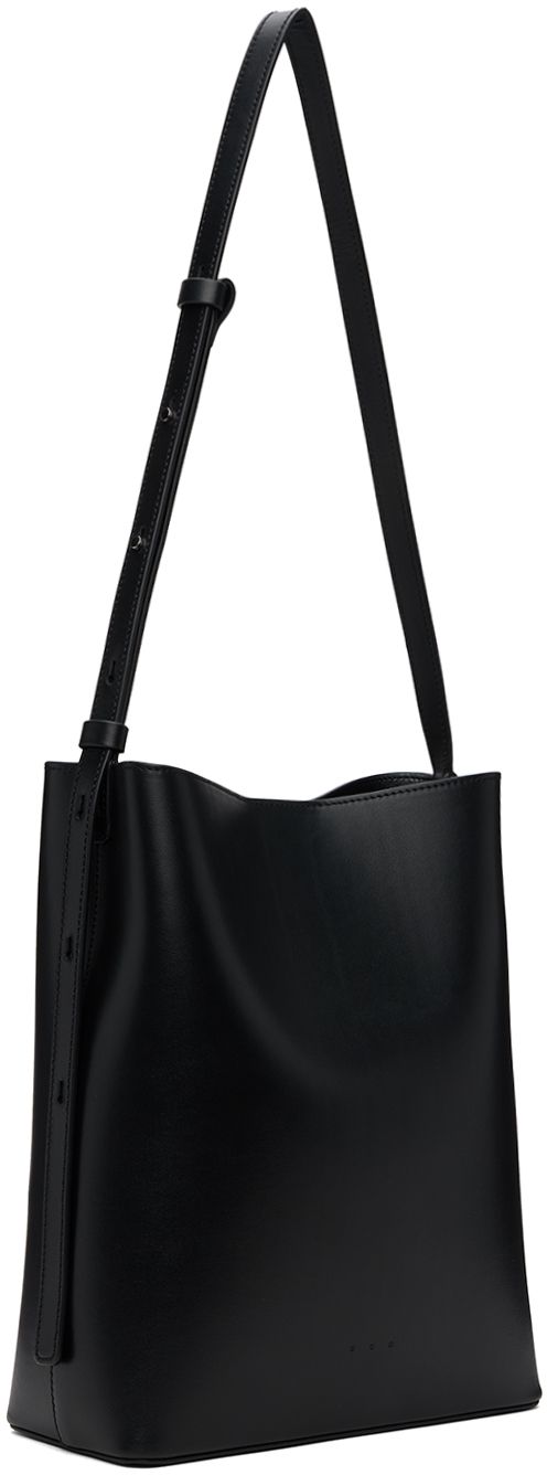 Buffed calfskin shoulder bag in black. · Adjustable crossbody strap · Logo embossed at face · Magnetic closure · Patch pocket at interior · Grained faux-leather lining · H11 x W9 x D4 Supplier color: Black Chic Textured Leather Bucket Bag For Business, Textured Leather Shoulder Bag For Office, Modern Business Crossbody Bucket Bag, Modern Black Textured Leather Satchel, Textured Leather Office Bucket Shoulder Bag, Formal Crossbody Bucket Bag With Adjustable Strap, Office Textured Leather Shoulder Bucket Bag, Textured Leather Bucket Shoulder Bag For Office, Evening Textured Leather Bucket Shoulder Bag