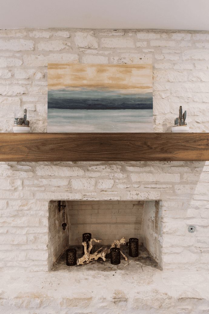 a white brick fireplace with a painting on the mantle