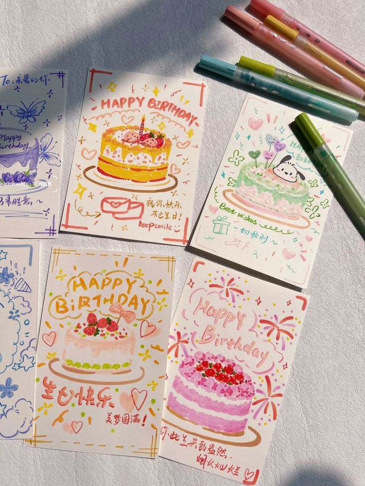 four happy birthday cards with colored pencils next to them