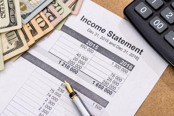 a calculator, pen and money on top of a paper with the word income statement