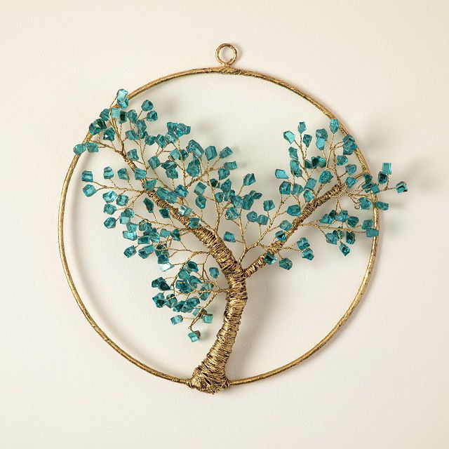 a wire tree with blue beads hanging on a wall