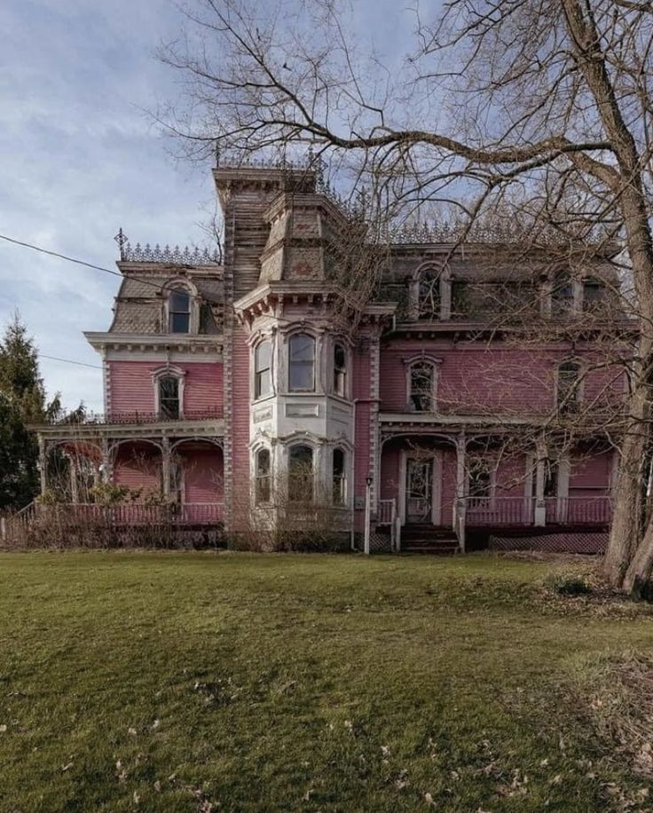 an old pink house is in the middle of a grassy area with trees and bushes