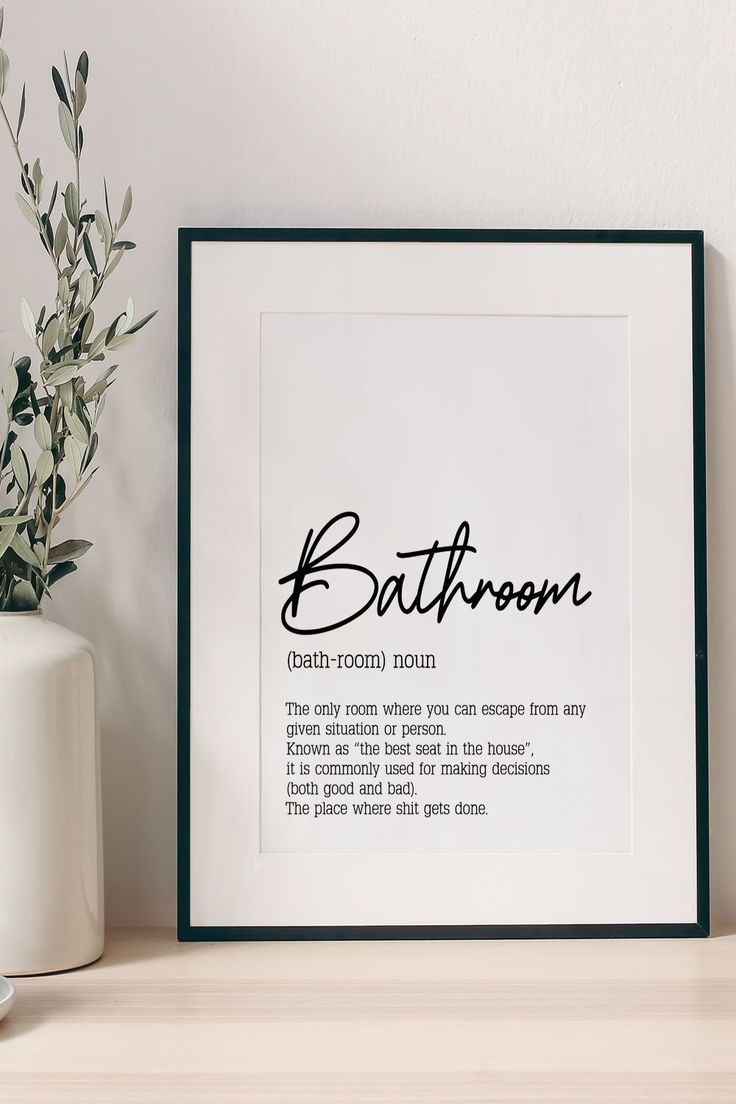 a bathroom print with the words bath room in cursive font on it next to a potted plant