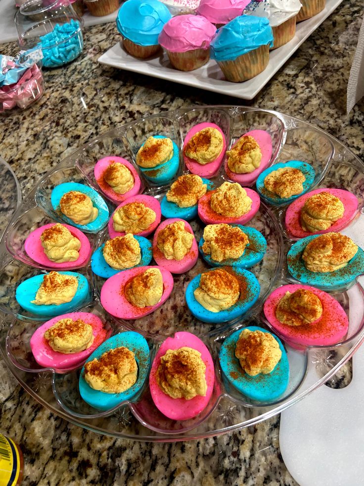 there are many cupcakes on the table with blue and pink frosting