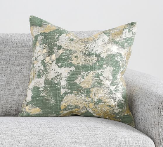 a green and yellow pillow sitting on top of a gray couch next to a white wall