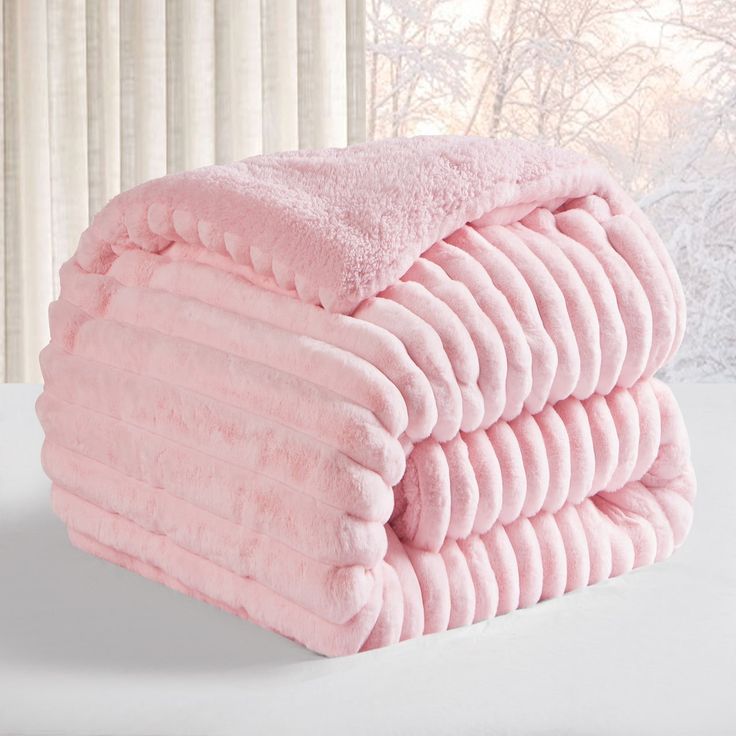 a pile of pink towels sitting on top of a white table next to a window