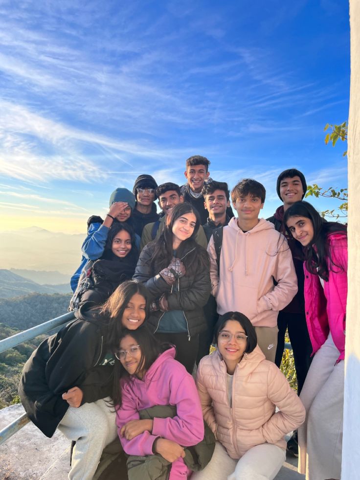 a group of people posing for a photo on top of a hill with mountains in the background