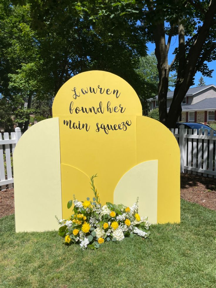 a yellow monument with flowers in front of it and a sign that says journey found her main squeezer