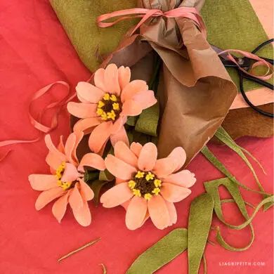 three pink flowers are sitting on top of a green pillow and some ribbon tied around it