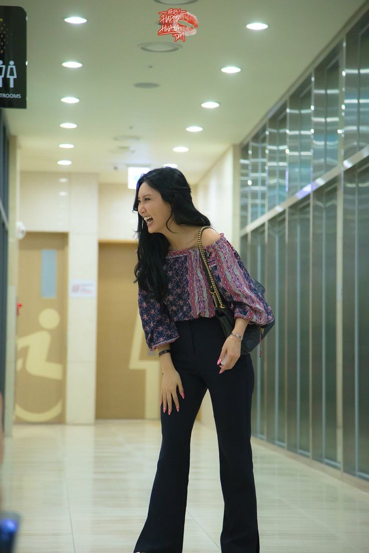 a woman standing in the middle of a hallway with her hand on her hip and smiling