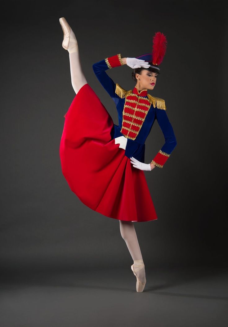 a woman in a red and blue dress is doing a ballet pose with her leg up