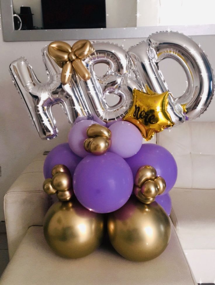 some balloons are stacked on top of each other with the word baby spelled out in gold and purple