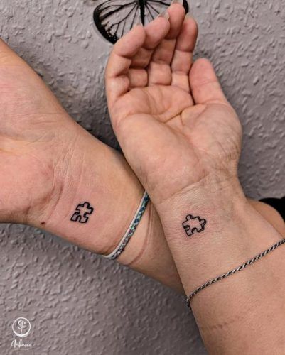 two people holding hands with small tattoos on their wrists and one is holding a butterfly