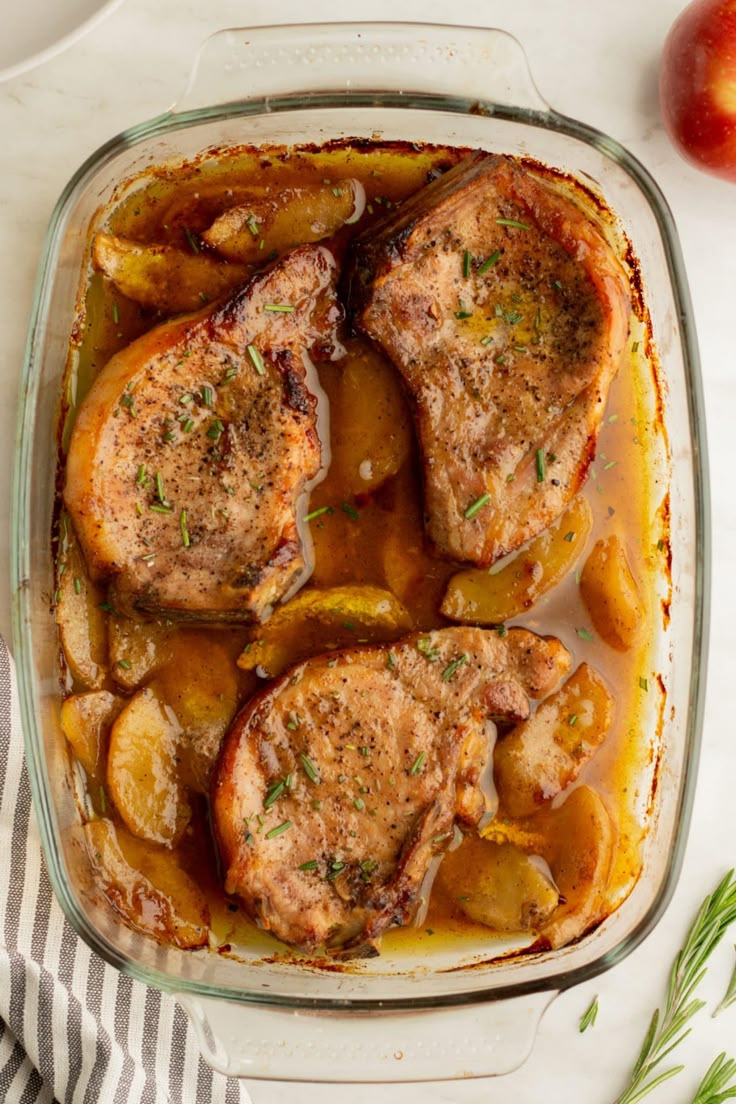 pork chops with apples and gravy in a glass casserole dish