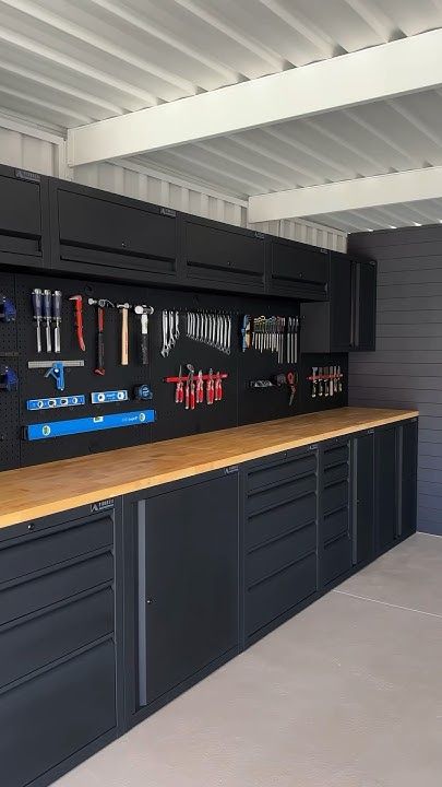 an organized garage with lots of tools on the wall and cabinets in front of it