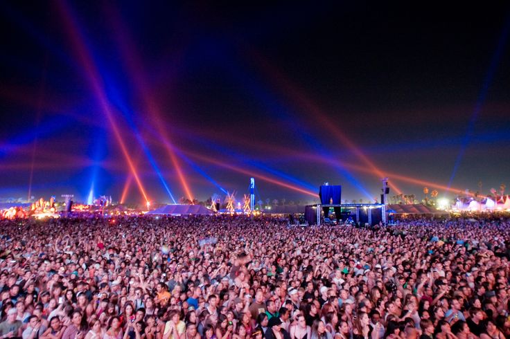 a large group of people standing in the middle of a field with lights on them