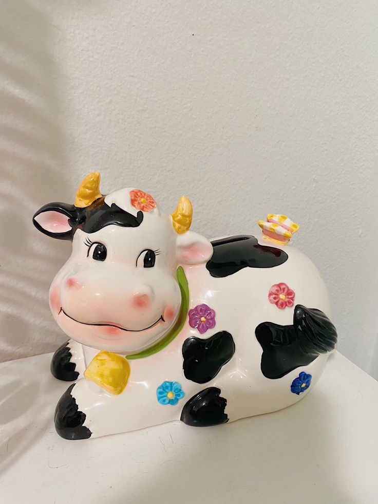 a cow figurine sitting on top of a white table next to a wall