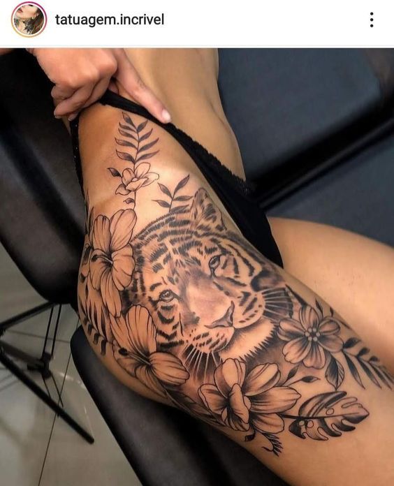 a woman's thigh with a tiger and flowers tattoo on her leg, sitting in a chair