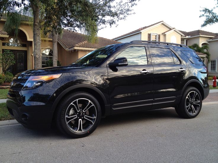 a black ford explorer is parked in front of a house on a residential street with palm trees