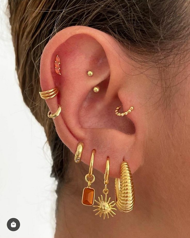 a woman wearing gold ear cuffs and earrings