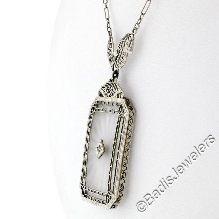 This is a gorgeous and VERY WELL MADE pendant necklace crafted during the art deco period in solid 14k white gold. It features a large, rectangular-shaped, camphor glass panel with cut corners and a stunning diamond set at its center. The pendant displays magnificent etching designs and open filigree work throughout its frame as well as the part that connects to the chain. The filigree work gives this piece its unique look and makes a special statement on this pendant. The lovely diamond is set White Hallmarked Jewelry For Evening, Vintage Diamond Cut Jewelry For Evening, Vintage Diamond White Diamond Necklace, Classic White Diamond Necklace Hallmarked, Classic White Hallmarked Diamond Necklace, Art Deco Platinum Jewelry For Evening, Art Deco Engraved Jewelry For Vintage Events, Engraved Art Deco Jewelry For Vintage Events, Antique Engraved Platinum Jewelry