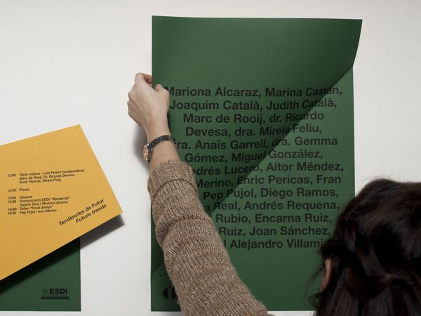 a woman is writing on a wall next to a green and yellow piece of paper