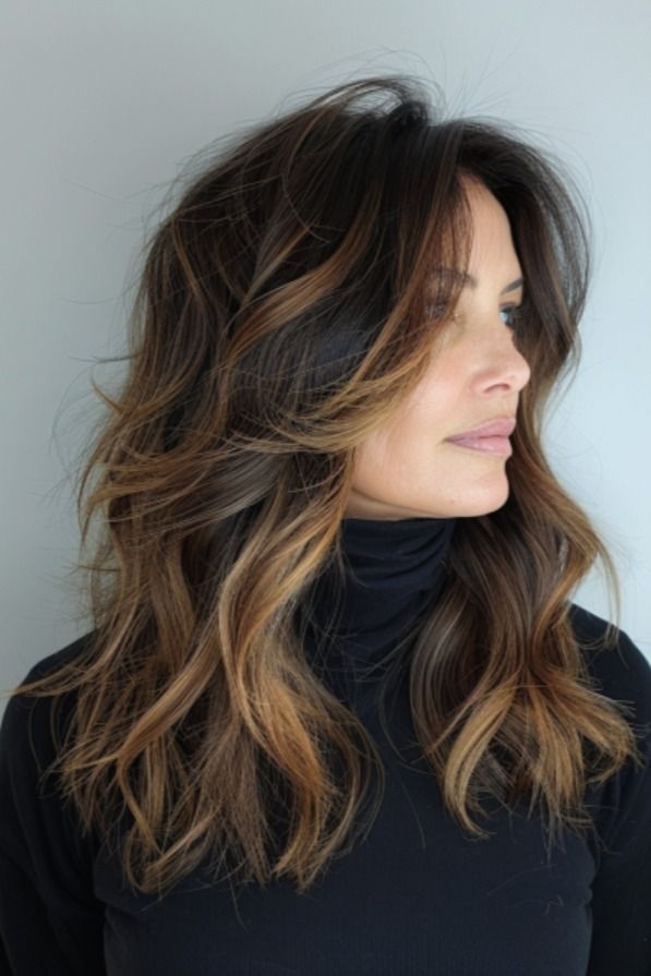 a woman with long, wavy hair wearing a black turtle neck sweater