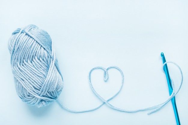 a ball of yarn next to a crochet hook with a heart on it