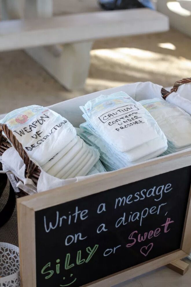 several diapers are in a basket on the floor next to a sign that says write a message on a diaper silly or sweet