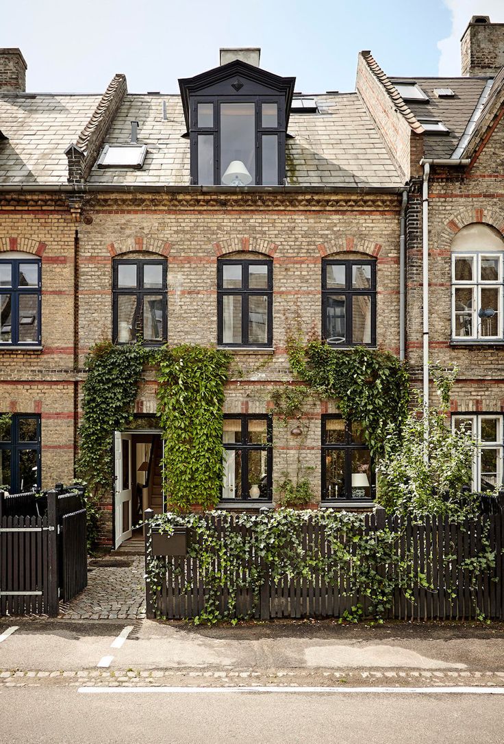 an old brick building with ivy growing on it's side and windows in the front