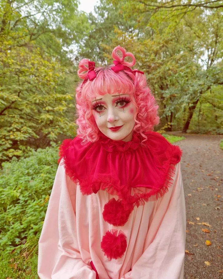 a woman with pink hair and makeup wearing a costume