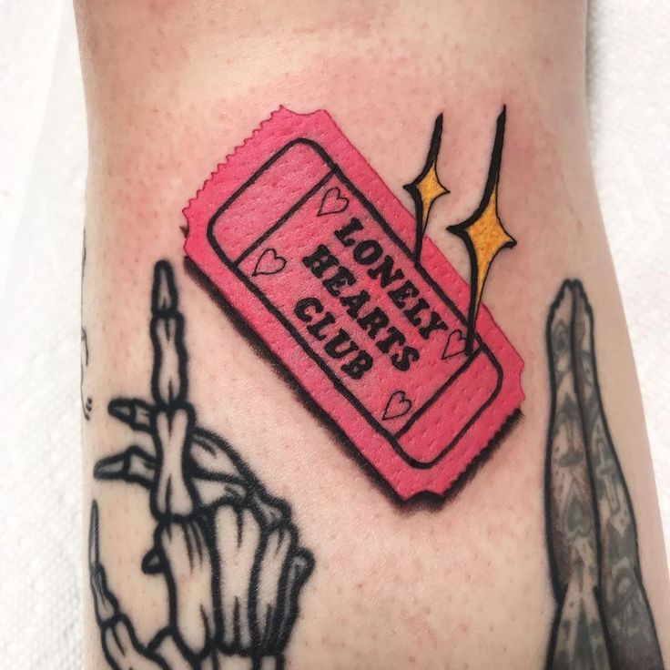 a tattoo with a pink ticket and scissors on it