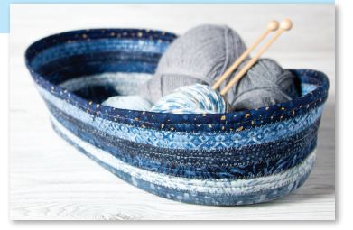 a blue bowl with yarn and knitting needles in it