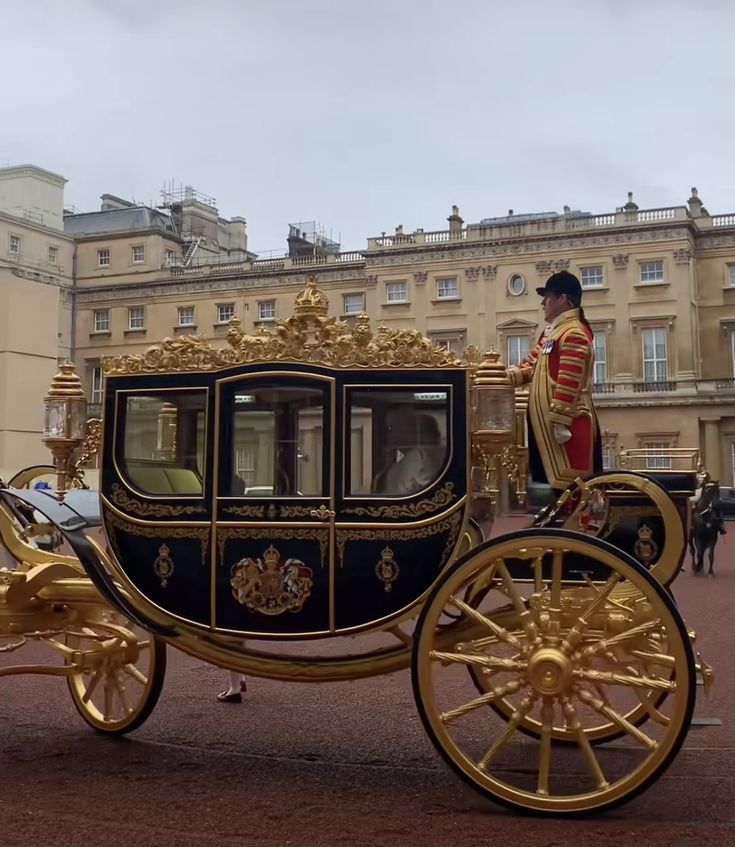 a gold and black carriage with a man in uniform on it's back riding down the street