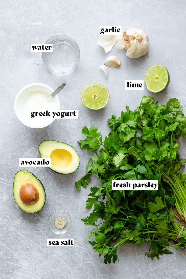 the ingredients to make an avocado salad laid out on a gray surface with white lettering