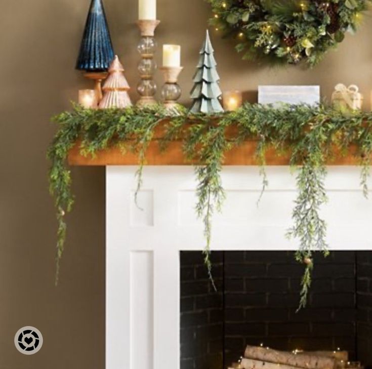 a mantel decorated with greenery, candles and wreaths on top of it