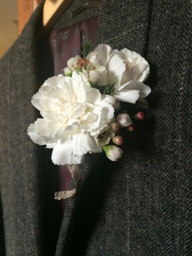 a boutonniere with white flowers attached to the lapel of a suit