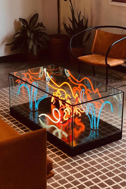 a glass table with neon lights on it in a room filled with chairs and couches