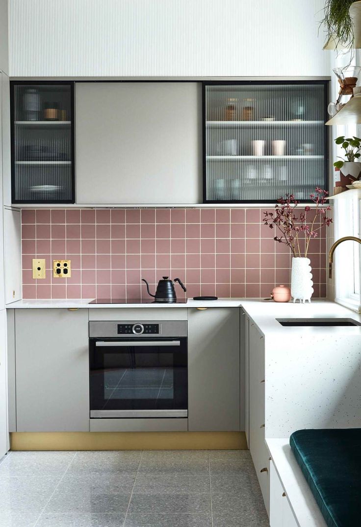 a kitchen with pink and white tiles on the wall