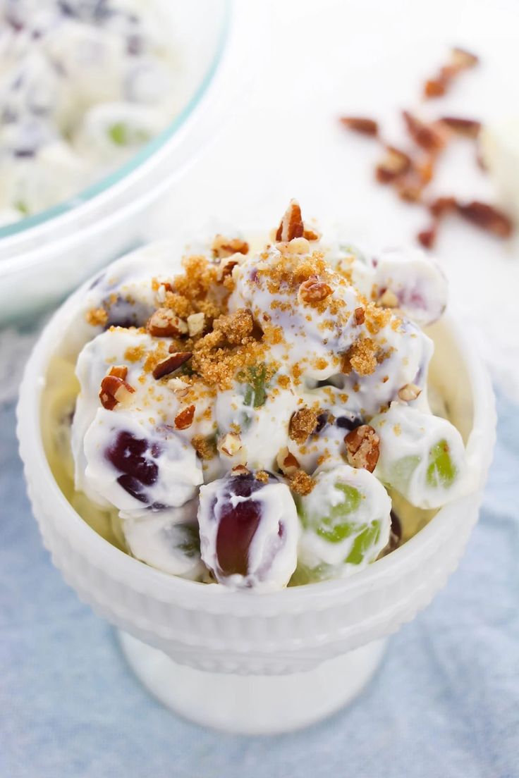 a white bowl filled with fruit salad on top of a blue cloth next to another bowl