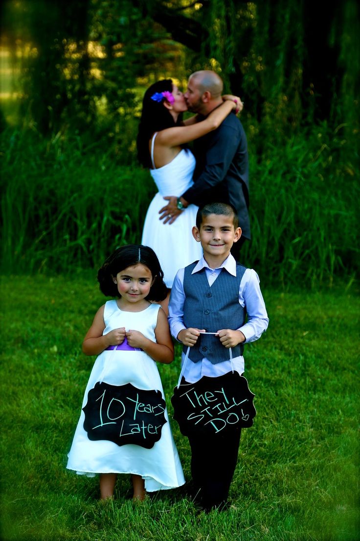 two children and an adult posing for a photo in front of some trees with chalk writing on them