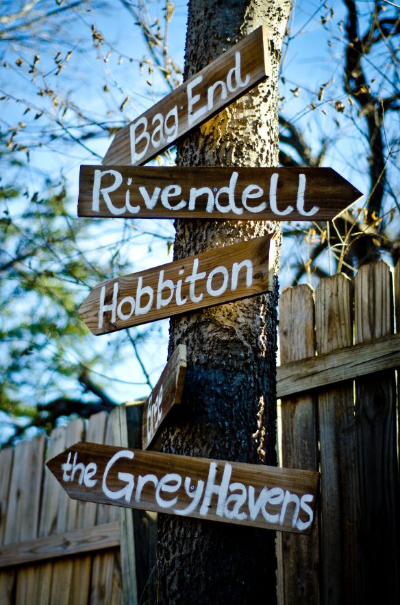 a wooden sign pointing to different locations on a tree