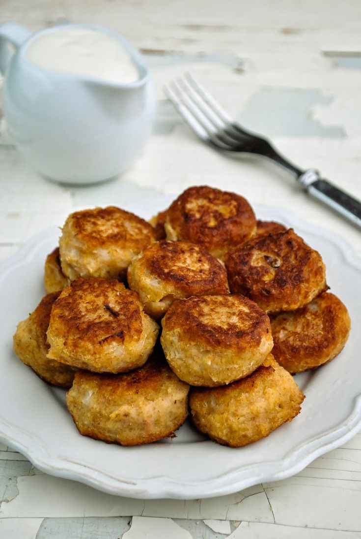 a white plate topped with biscuits next to a cup of milk and a silver fork