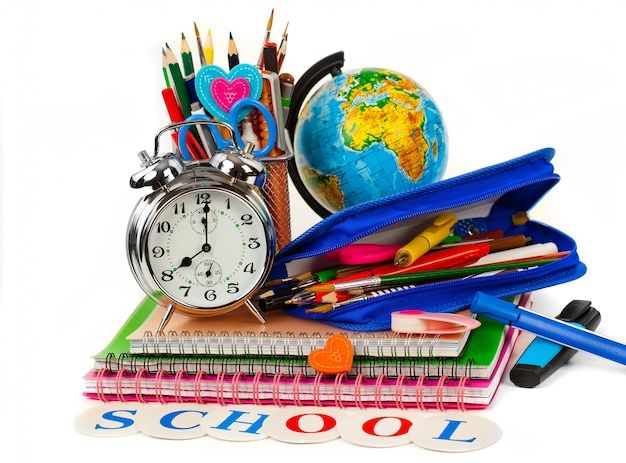 an alarm clock, pencils, and other school supplies are on top of each other